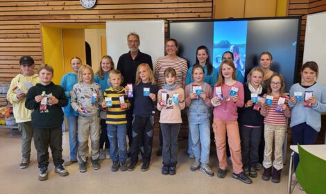 Alle Kinder mit bestandener Prüfung stehen nebeneinander und halten ihre Segelscheine in den Händen. Die Lehrer stehen dahinter.