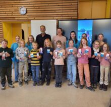 Alle Kinder mit bestandener Prüfung stehen nebeneinander und halten ihre Segelscheine in den Händen. Die Lehrer stehen dahinter.